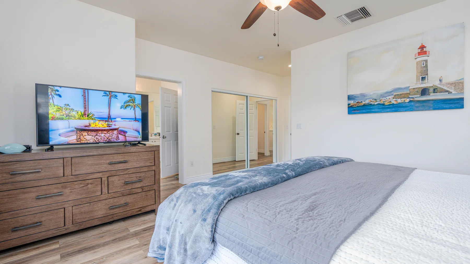 Un dormitorio con una cama, una cómoda de madera y un televisor.