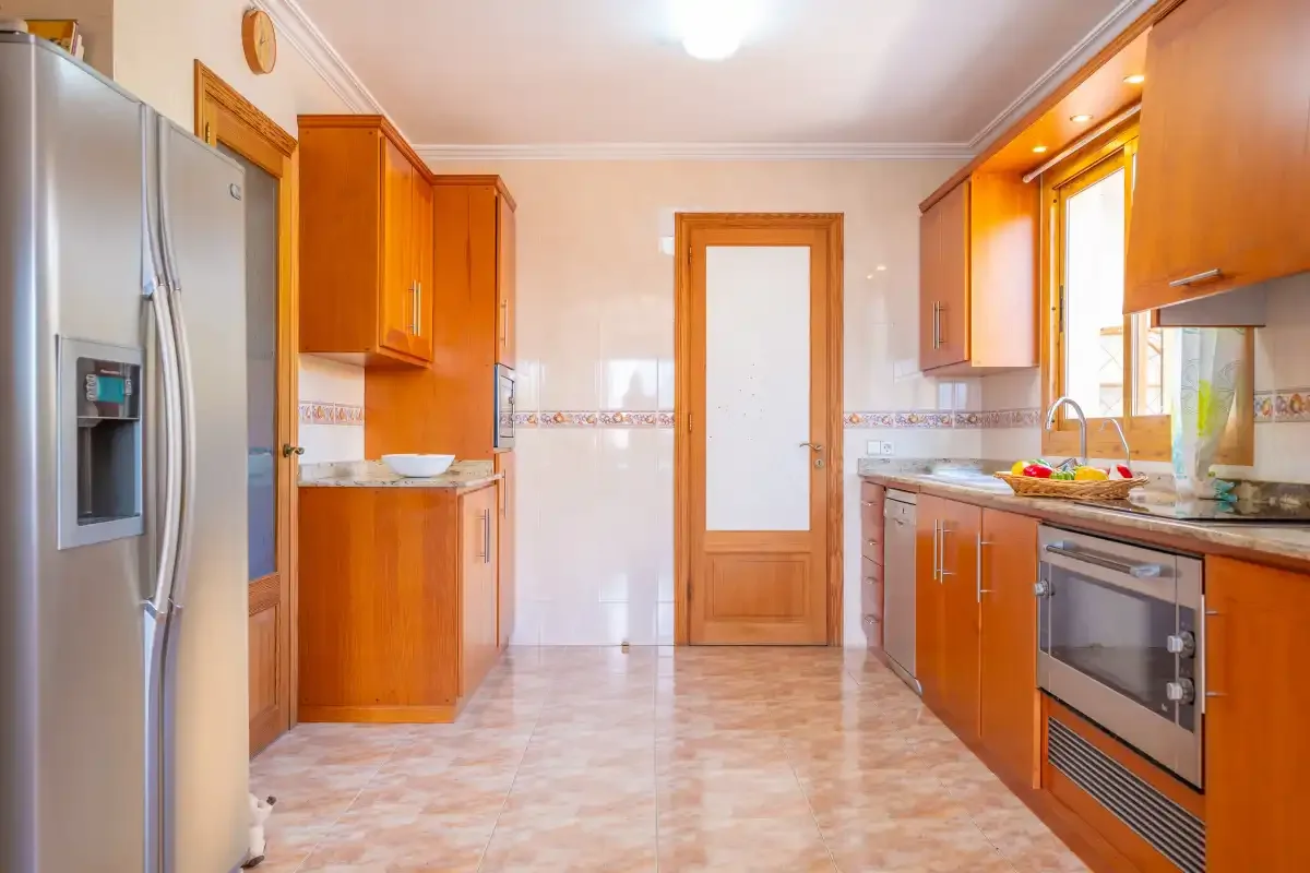 A bright kitchen with wooden cabinets and a refrigerator.