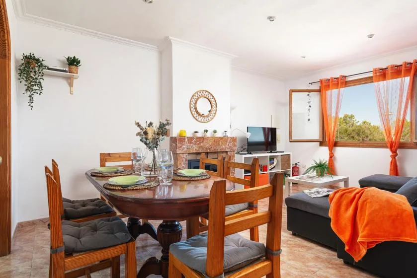 A dining and living area with a wooden dining table and seating by a large window.