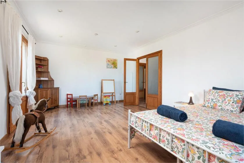 A bright bedroom with floral bedding and wooden flooring.