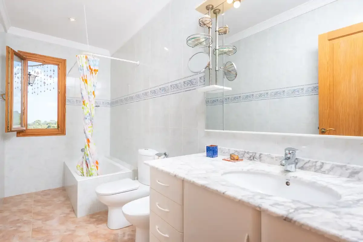 A bathroom with a bathtub, toilet, and sink beneath a wall mirror.