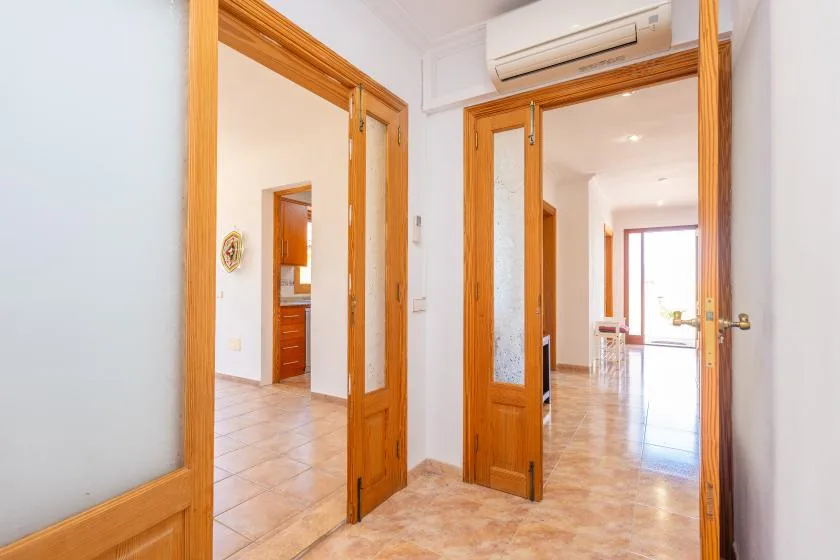 A bright interior hallway opens through wooden doorways into adjoining rooms.