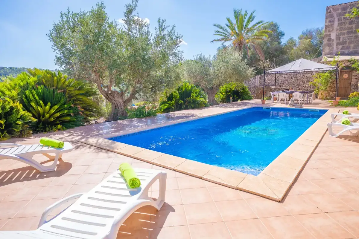 An outdoor swimming pool is surrounded by lounge chairs and greenery.