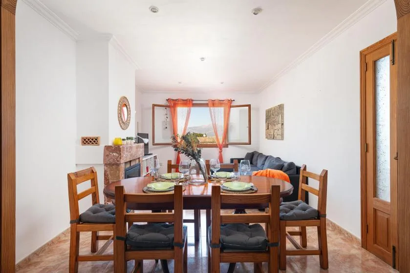 Dining area with a wooden table and seating beside a living area.