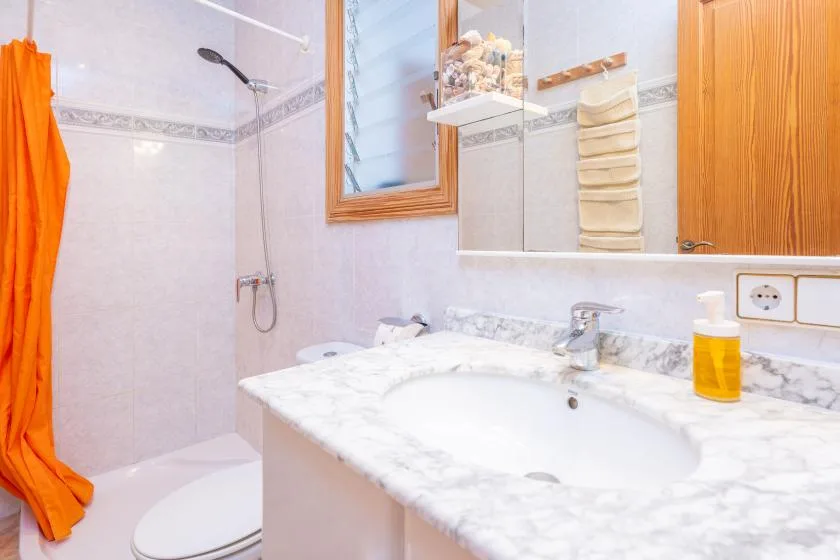 A bathroom with a bathtub, sink, and orange shower curtain.