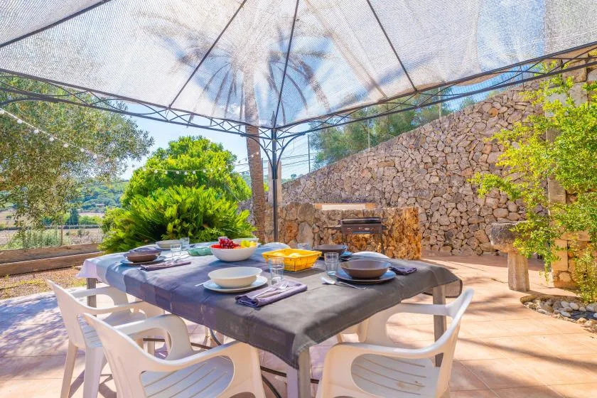 An outdoor dining area under a canopy, with a table set for a meal.