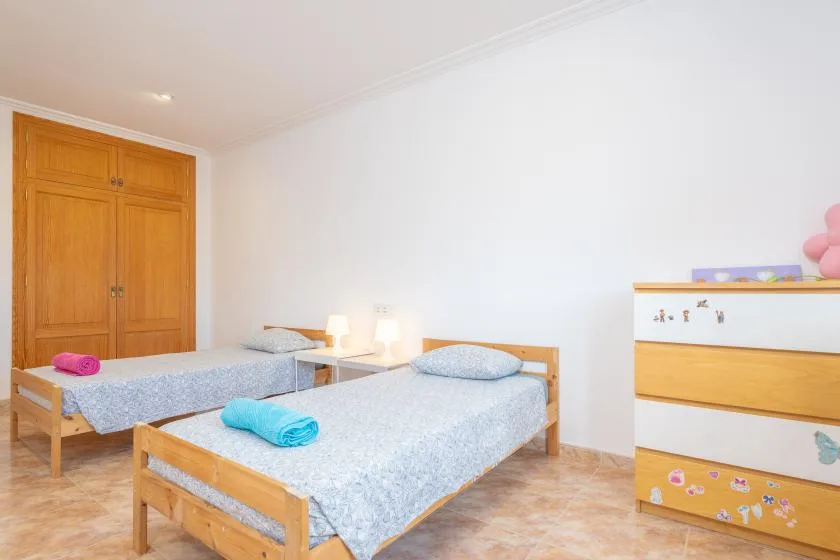 A bedroom with two single beds and wooden wardrobes.
