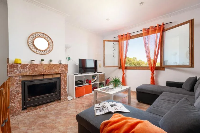 A living room with a fireplace, television, and seating beside a large window.