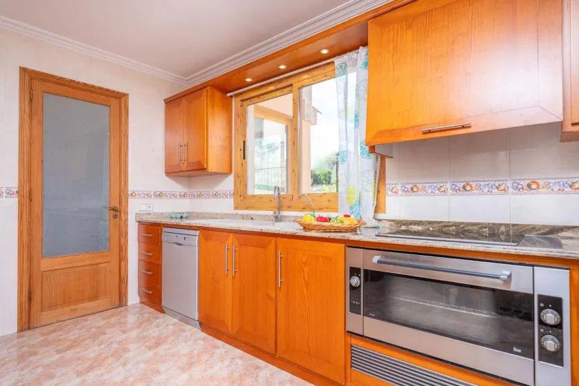 A bright kitchen with wooden cabinets, a window, and built-in appliances.