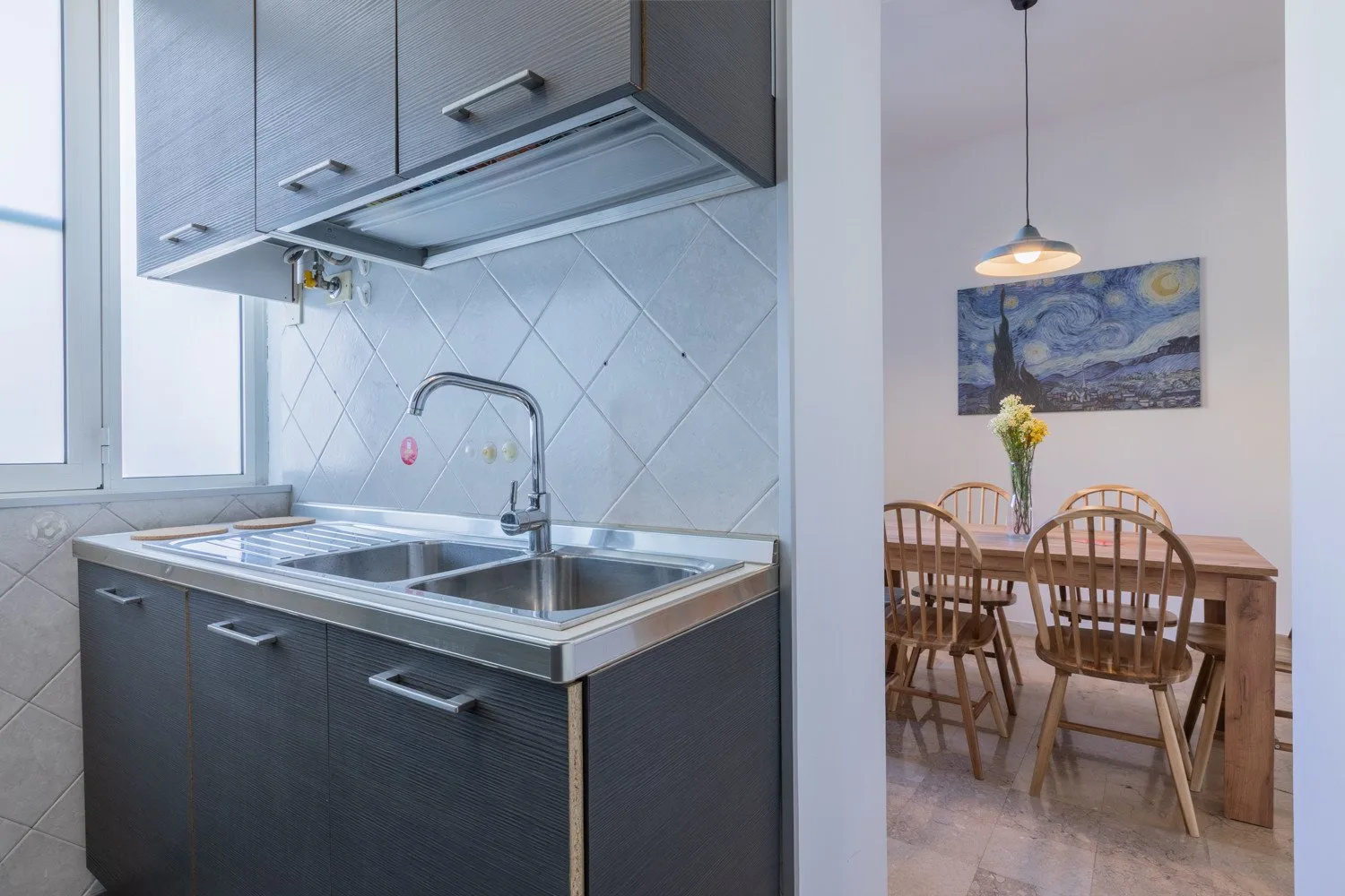A compact kitchen with a stainless-steel sink opens onto a dining area.