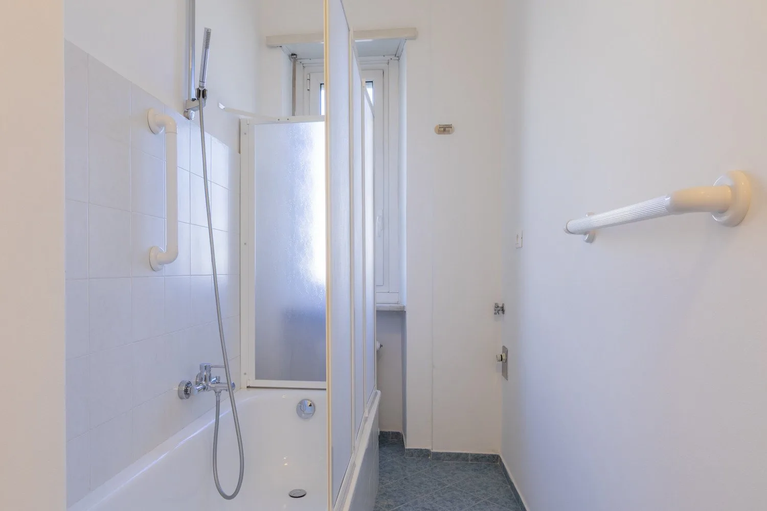 A bathroom with a bathtub, shower, and grab bars.