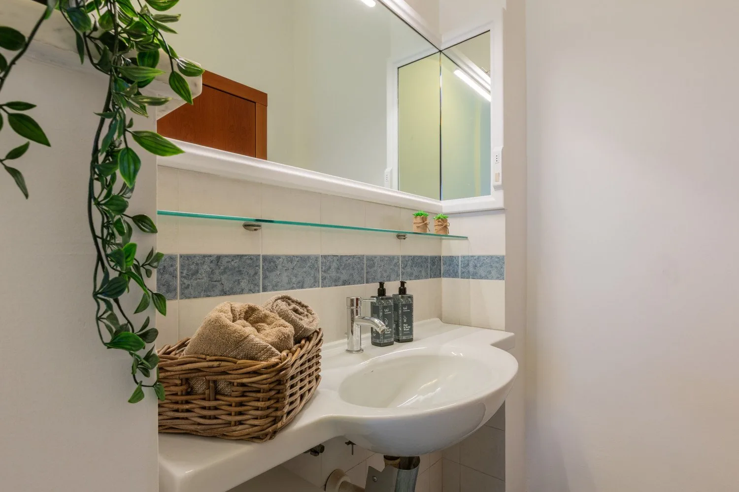 A bathroom vanity with a sink, mirror, and basket of folded towels.