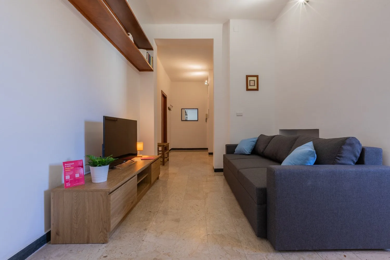 A living room with a television on a wooden console and a gray sectional sofa.