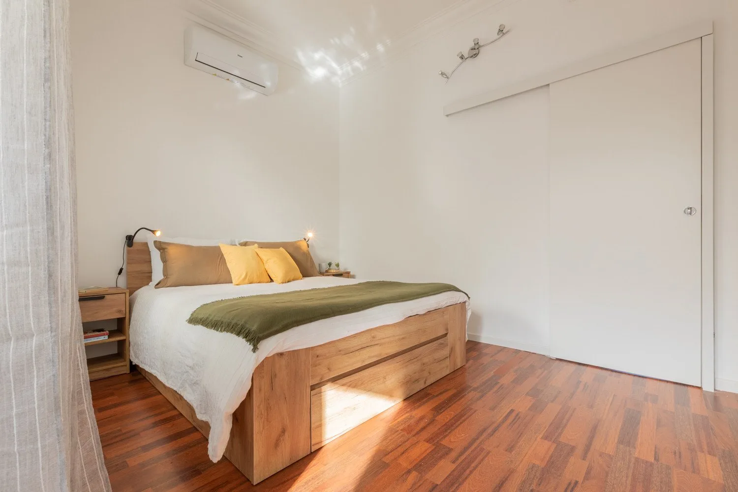A bedroom with a wooden bed and a green blanket.