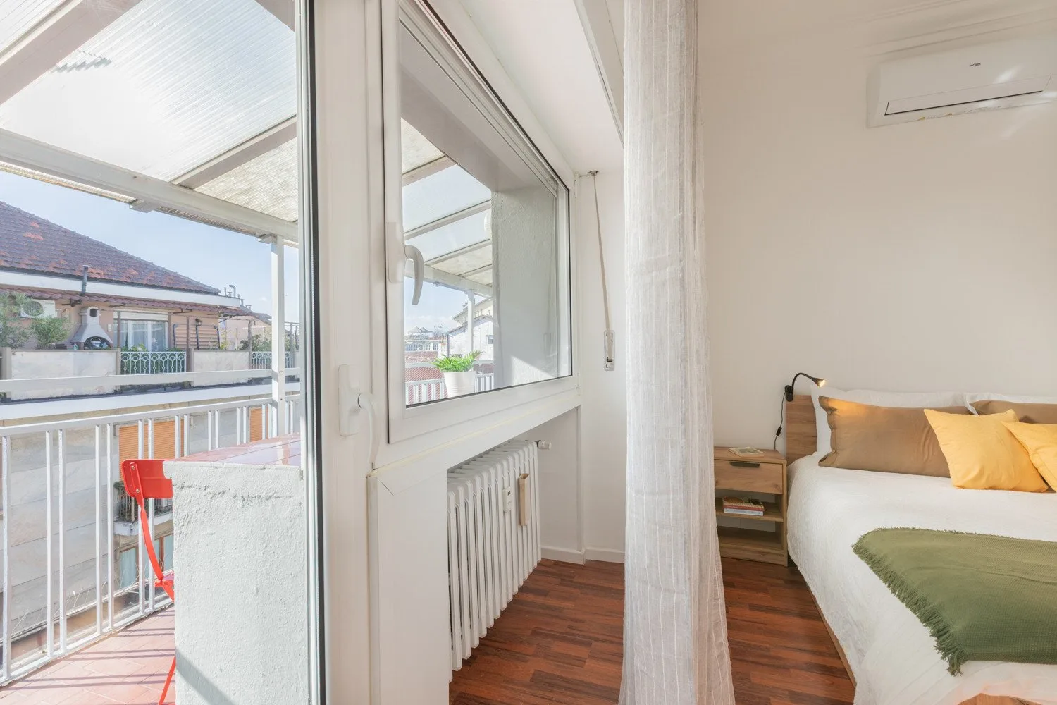 A bedroom with a bed beside large glass doors opening onto a balcony.