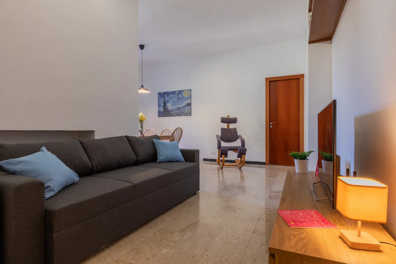 A living room with dark seating, a television, and a wooden coffee table.
