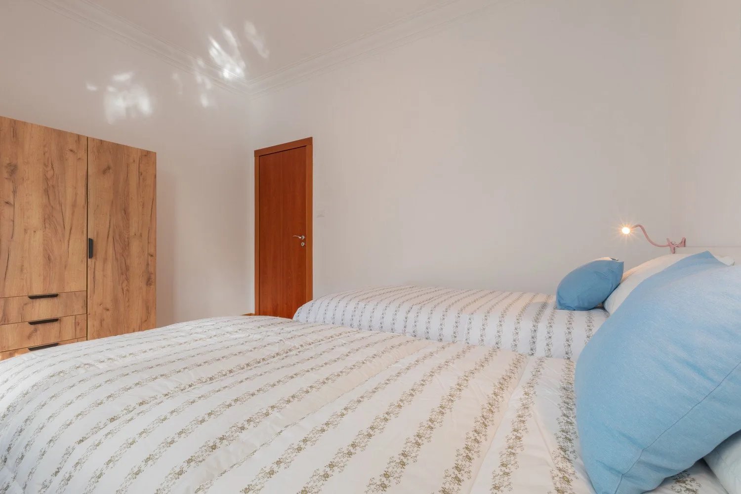 A bedroom with a striped bedspread and blue pillows.