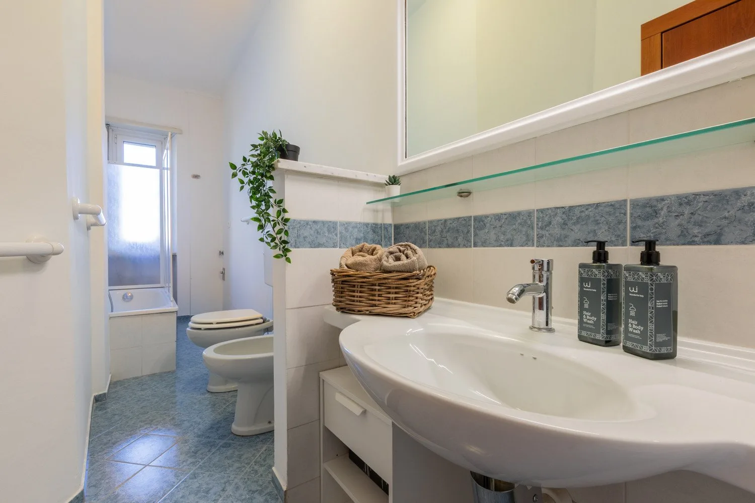 A bathroom with a wide sink, mirror, and toilet.