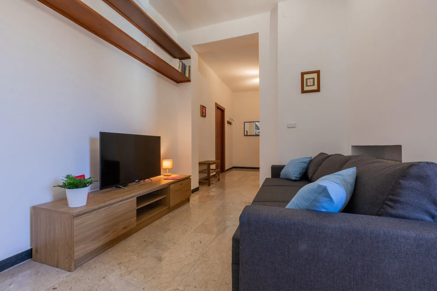 A living room with a television on a wooden console and a dark sofa.