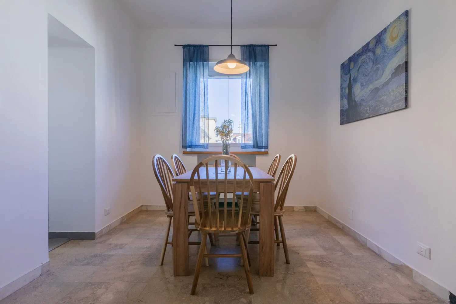 A dining area with a wooden table and chairs beneath a pendant light.