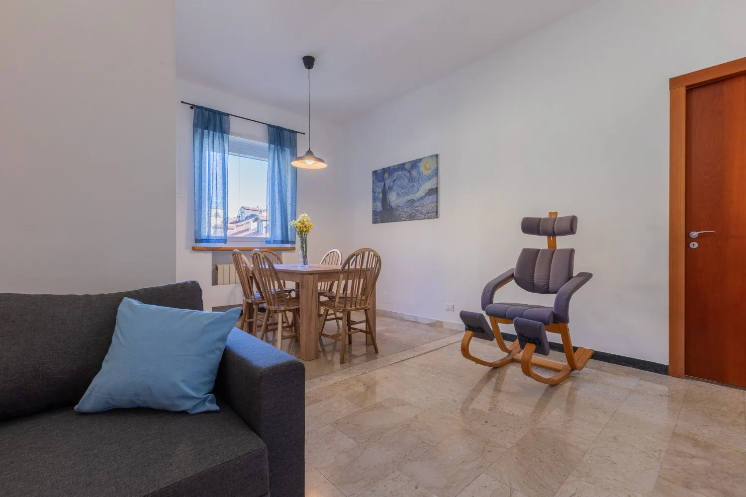 A living and dining area with a dark sofa, wooden table, and rocking chair.