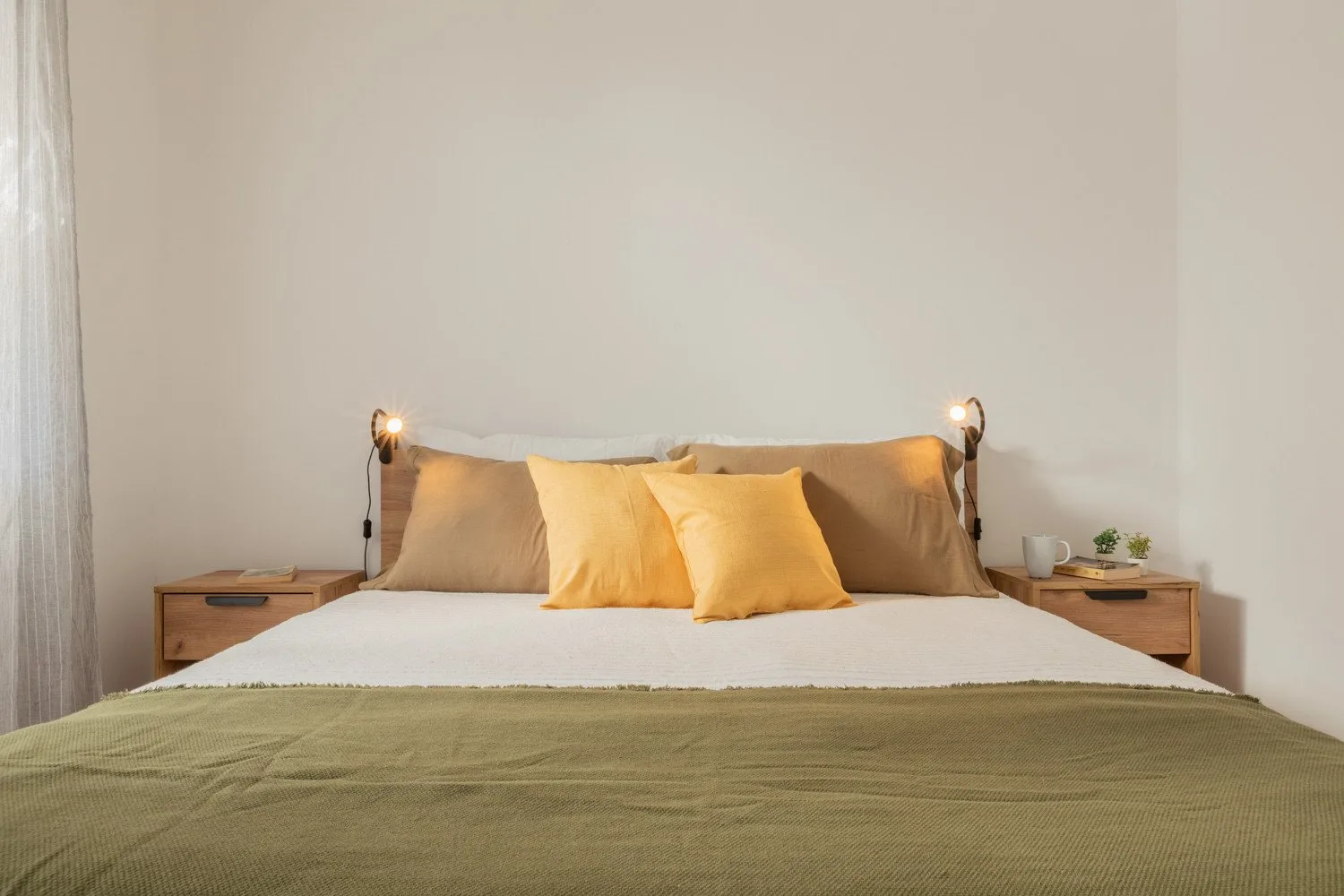 A bedroom with a neatly made bed and warm bedside lights.