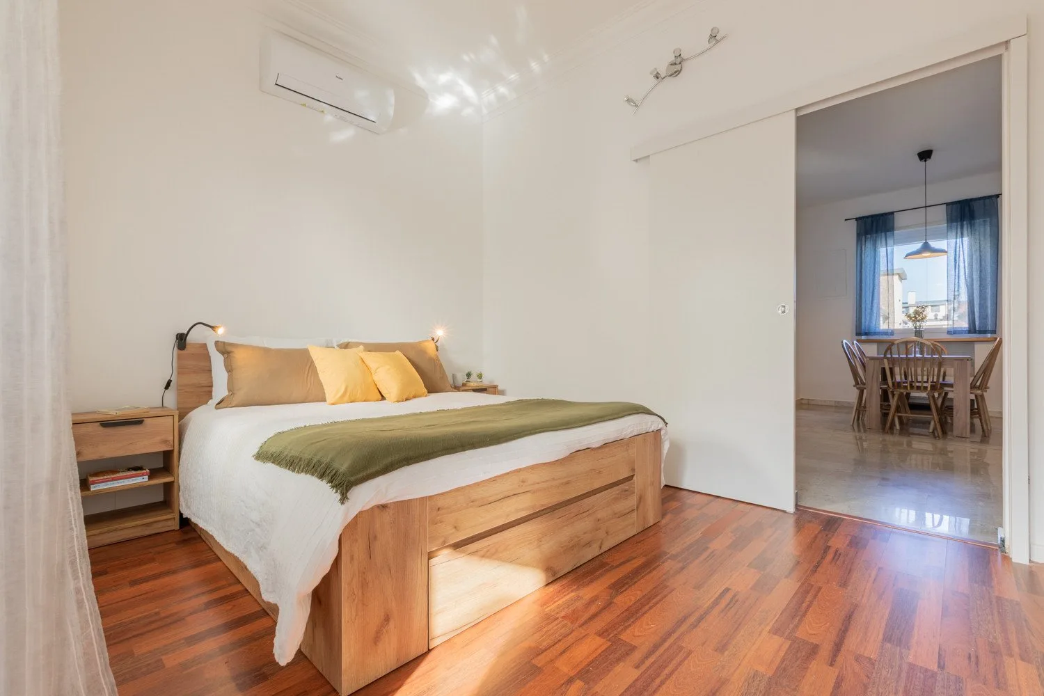 A bedroom with a wooden bed and an open doorway to a dining area.
