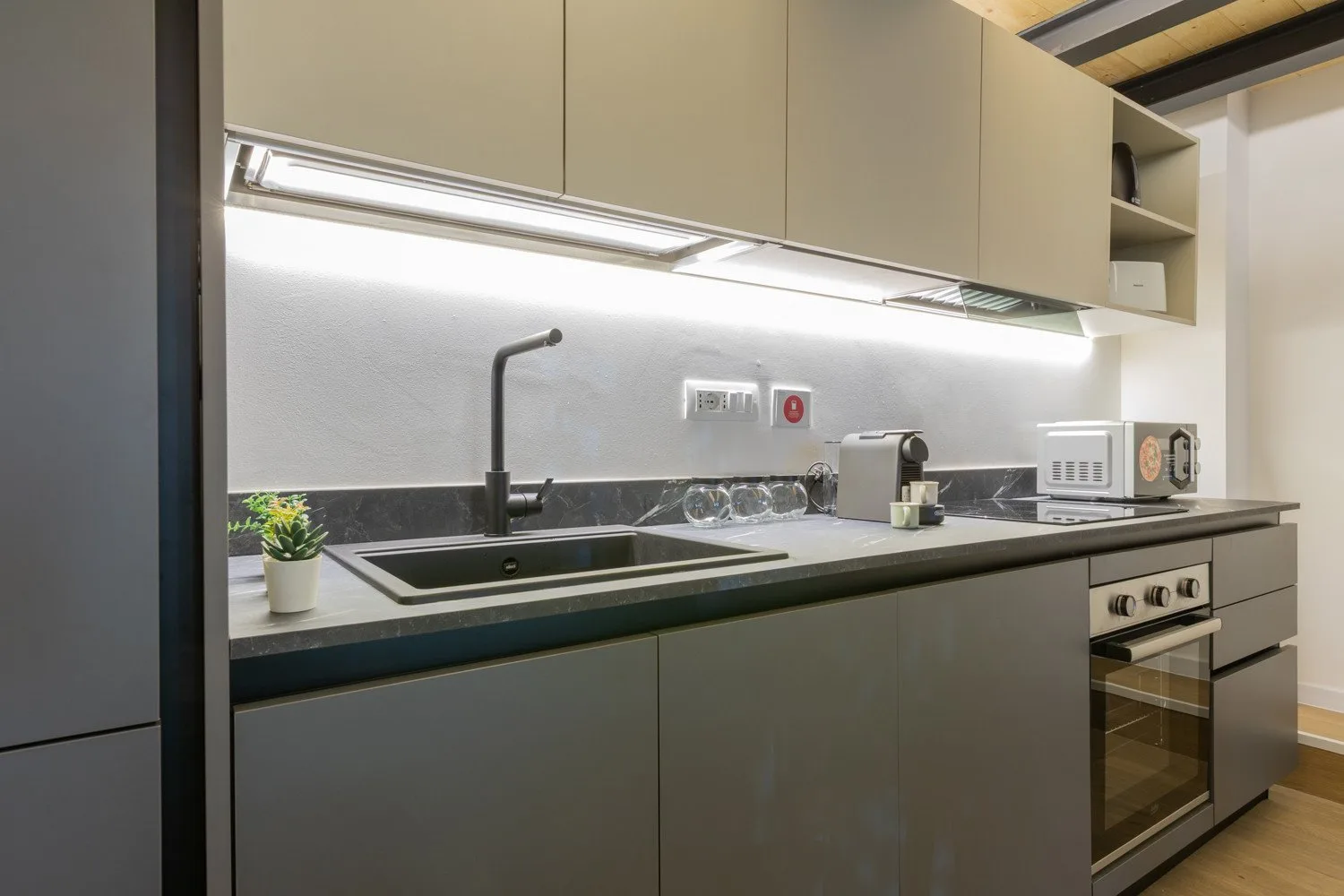 A modern kitchen with a sink, countertop, and built-in oven.