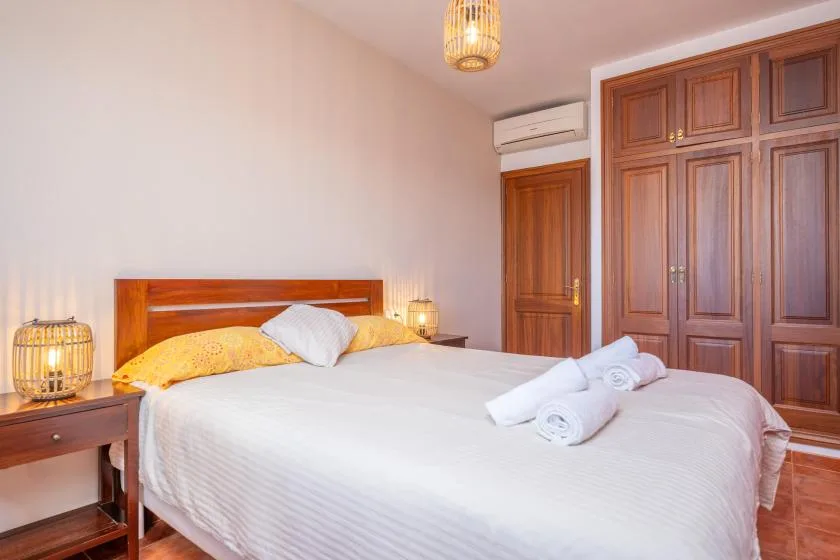 Un dormitorio con una cama bien hecha y armarios de madera.