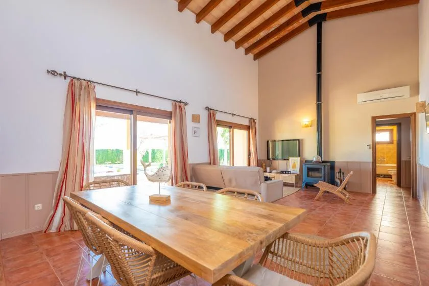 Un comedor y sala de estar con una mesa de madera, asientos y vigas expuestas.