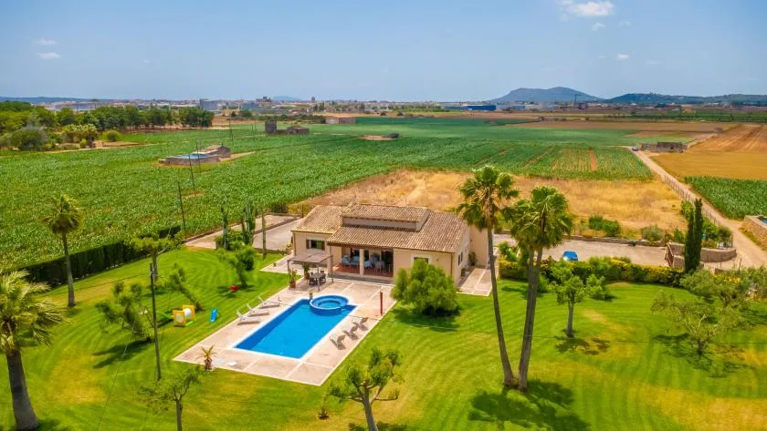 Una casa y una piscina se encuentran entre campos verdes y terrenos agrícolas.