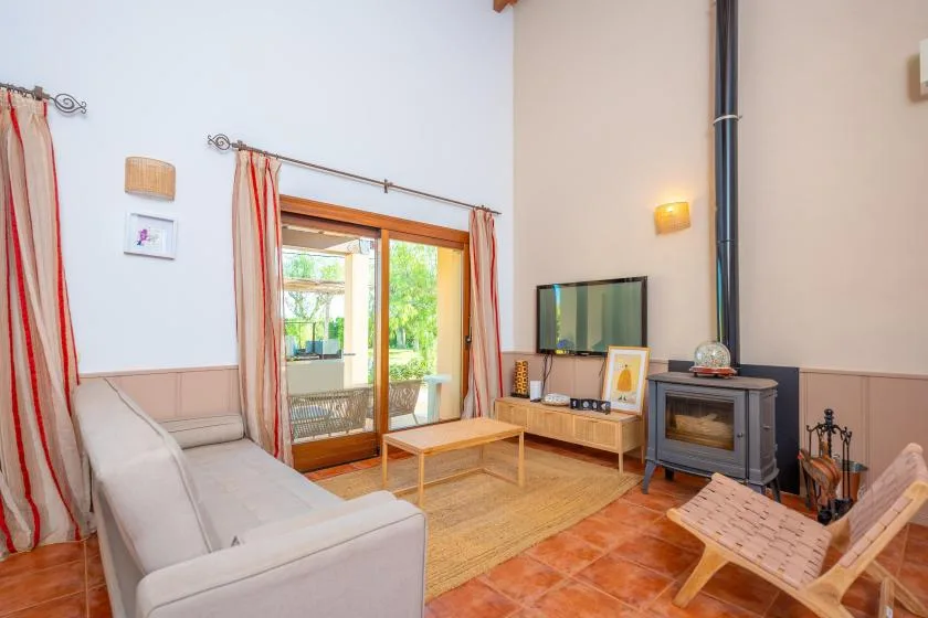 Una sala de estar con zona para sentarse, televisor y estufa de leña.
