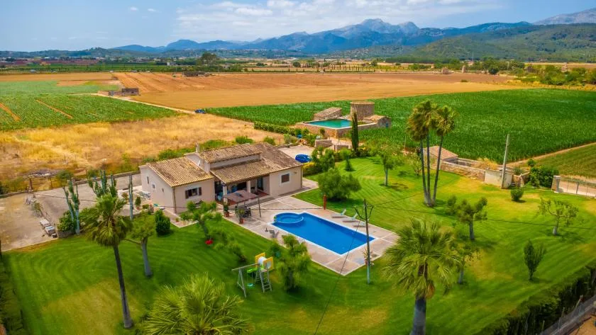 Una propiedad rural con piscina y césped verde, rodeada de campos.