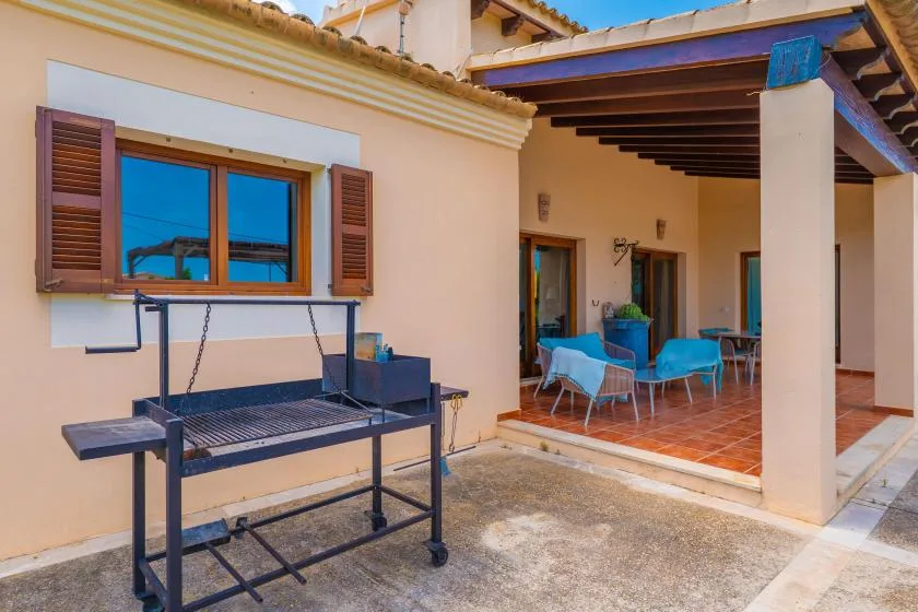 Un patio sombreado con asientos al aire libre y una parrilla junto a la casa.