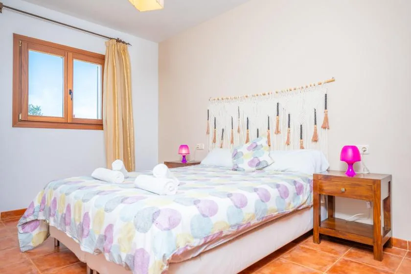 Un dormitorio con una cama doble cubierta con una colcha de estampado pastel.
