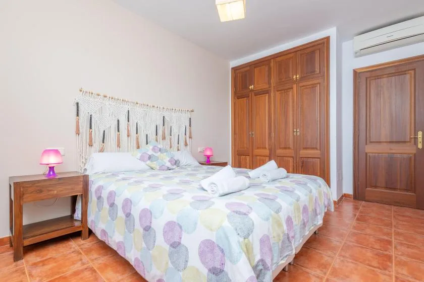 Un dormitorio con una cama doble, ropa de cama colorida y armarios de madera.