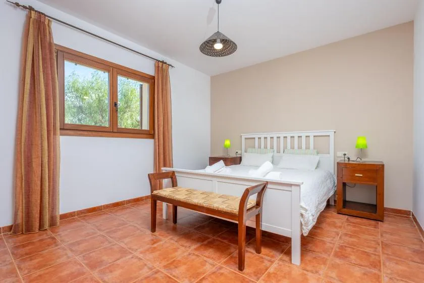 Un dormitorio con una cama, una mesa de madera y una ventana con cortinas.
