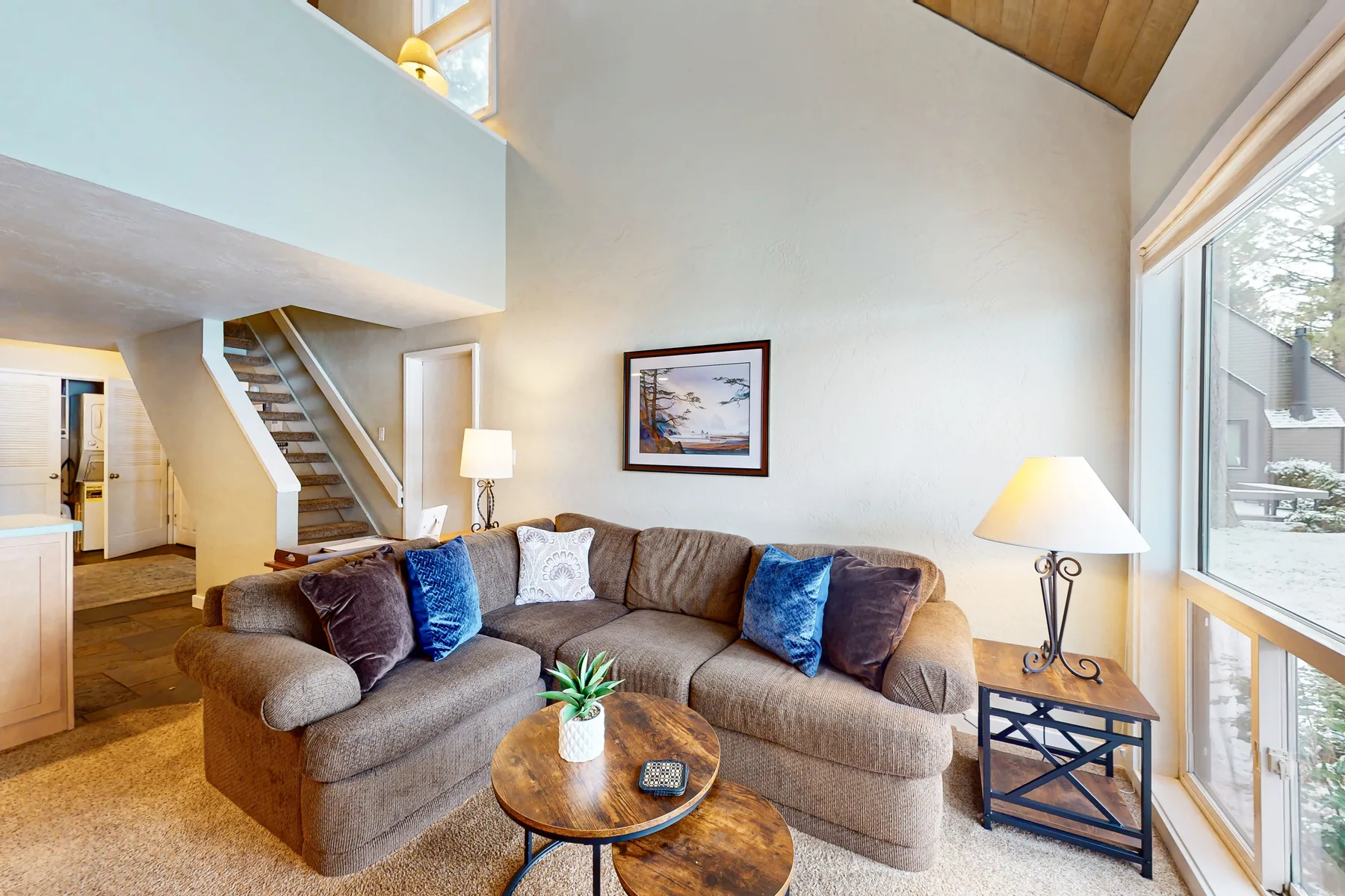 A bright living room with corner seating beside a large window.