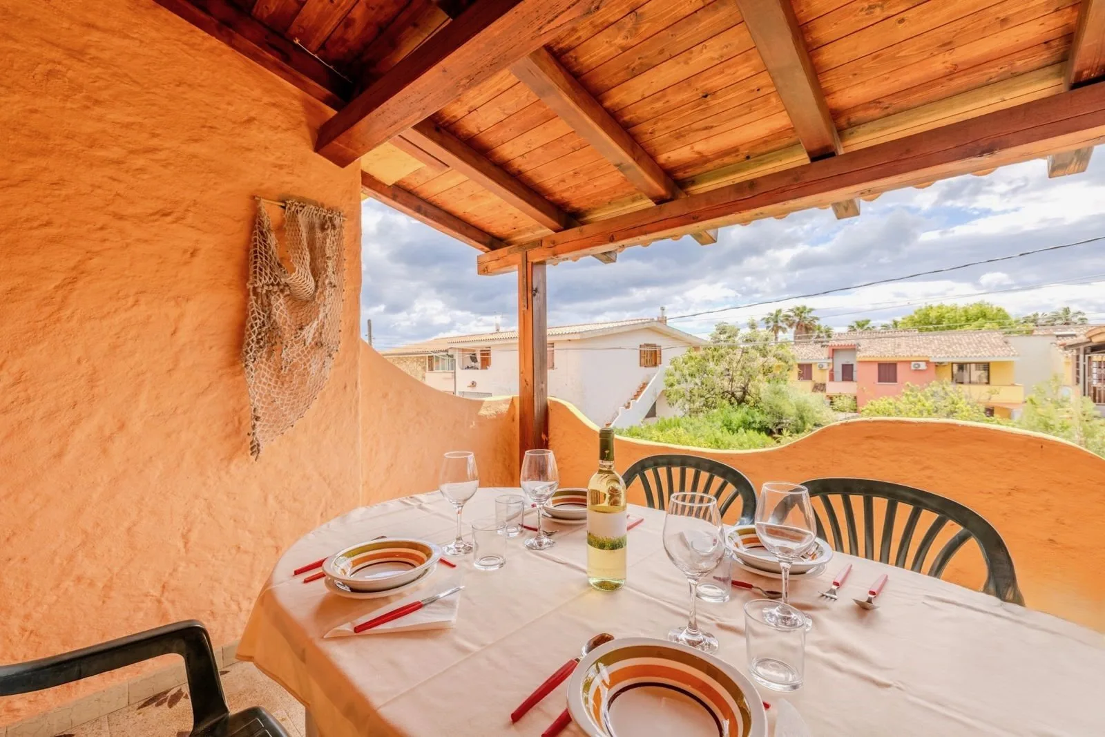 A covered outdoor dining area with a set table and a view of nearby buildings.
