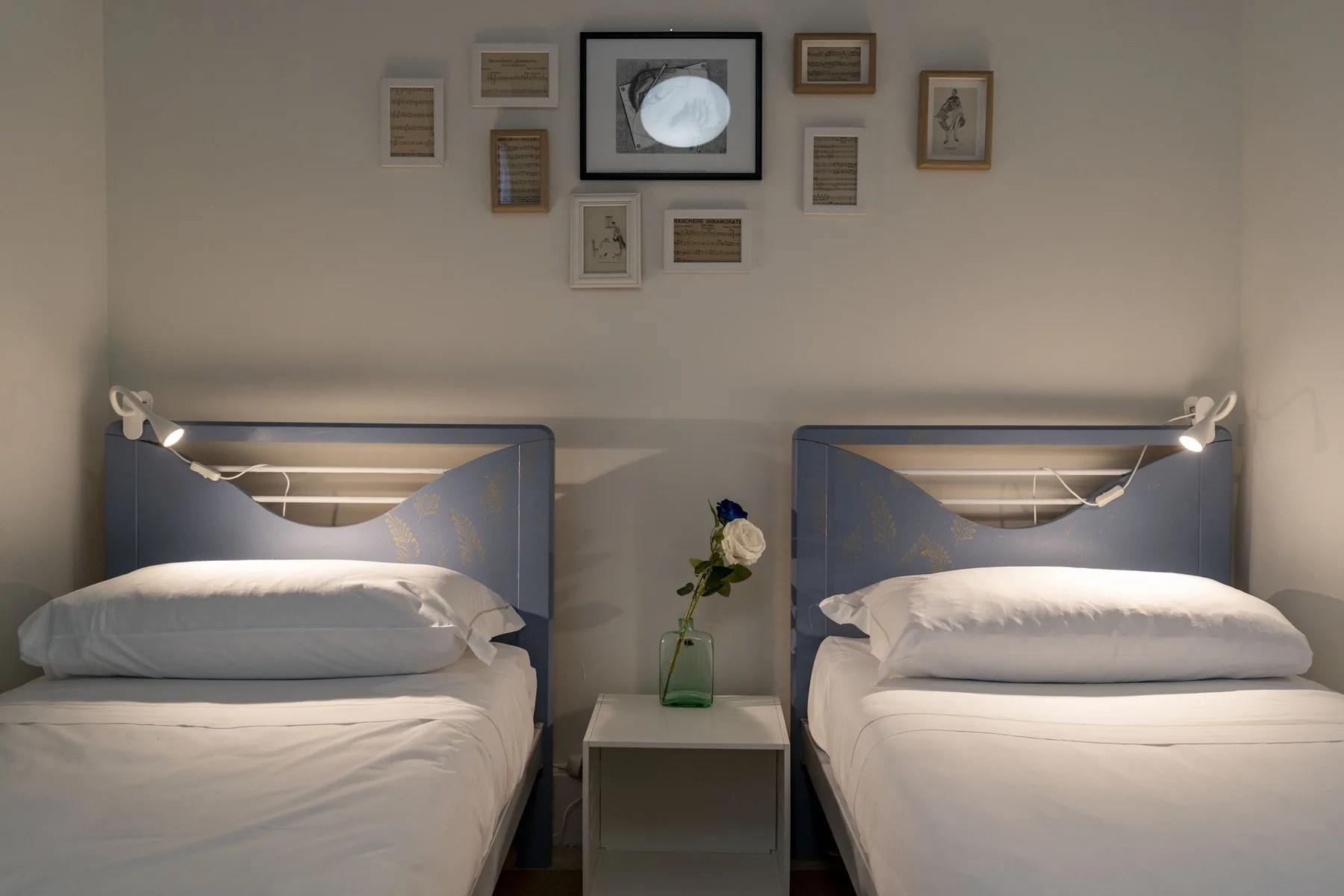 Un dormitorio con dos camas y luces junto a ellas.