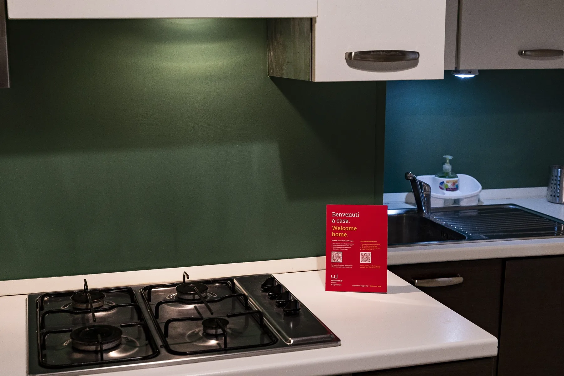 Una encimera de cocina con una estufa de gas, fregadero y salpicadero oscuro.