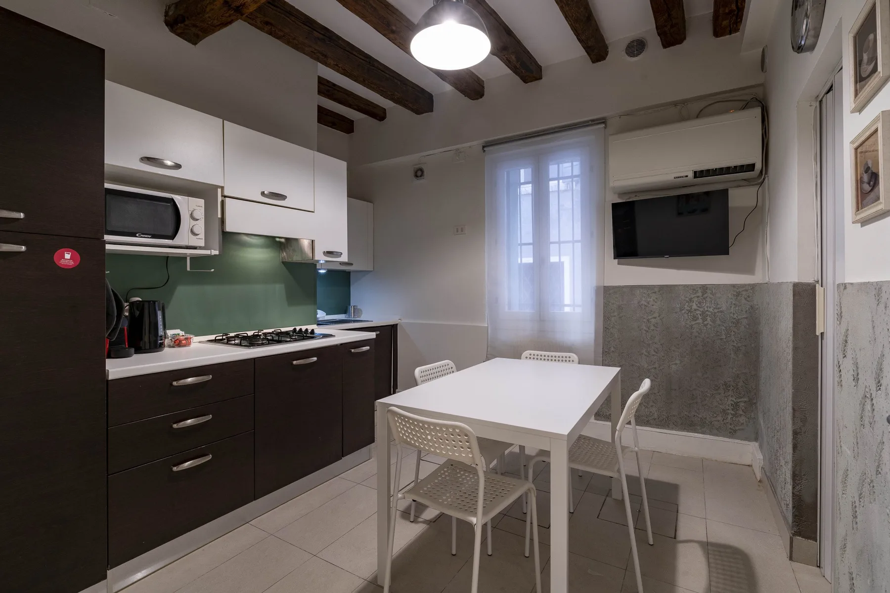 Una cocina compacta con zona de comedor y una mesa blanca junto a la encimera.