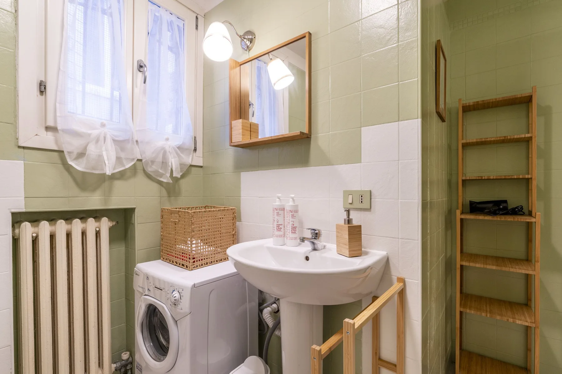 Un baño con azulejos, lavabo, lavadora y ventana.