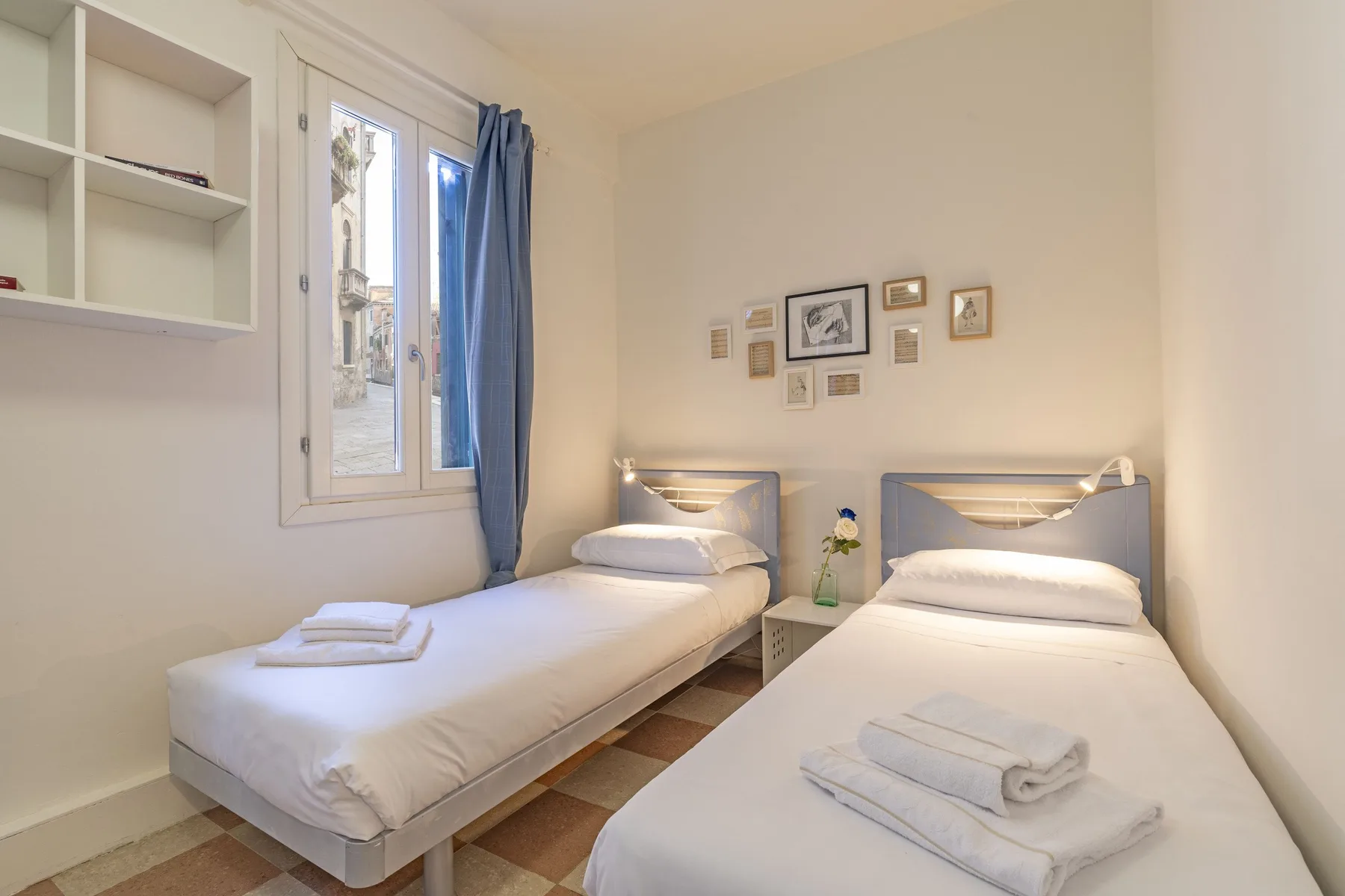 Un dormitorio con dos camas individuales y una ventana con cortinas azules.