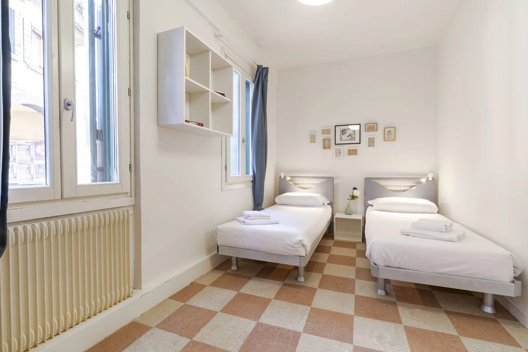 Un dormitorio luminoso con dos camas individuales y una pequeña mesita de noche.