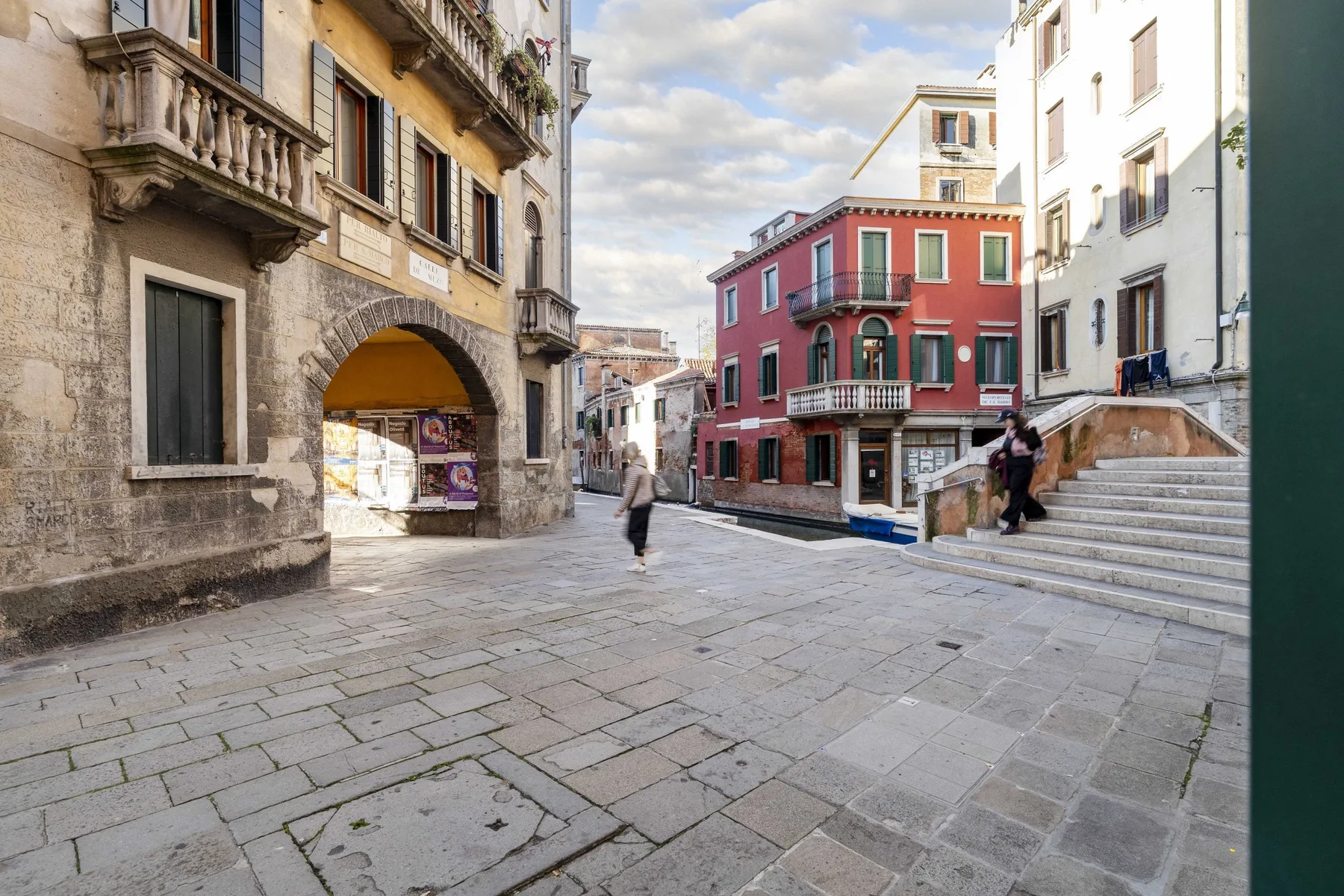 Una plaza peatonal pavimentada está rodeada de edificios coloridos y amplios escalones de piedra.