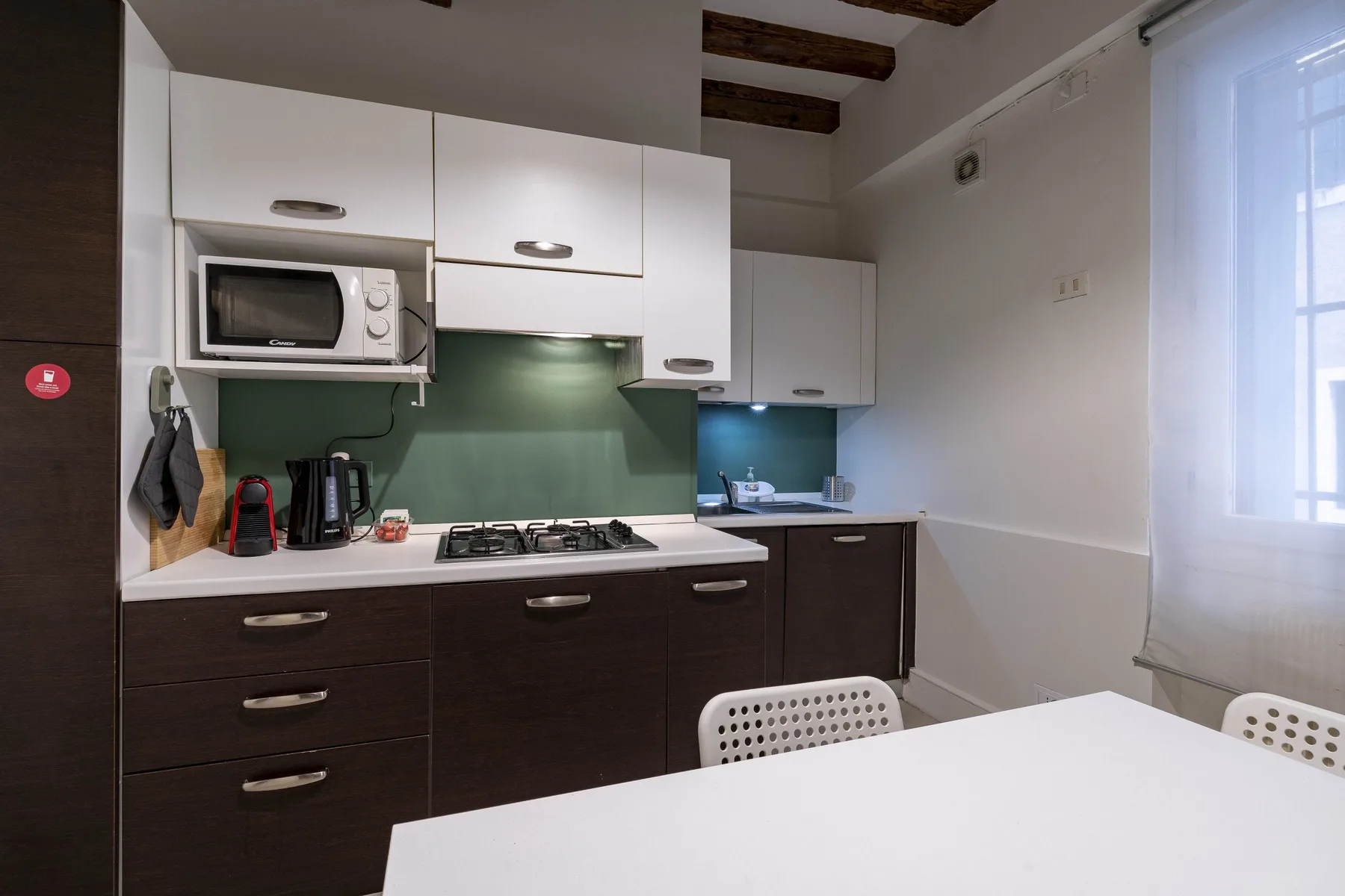 Una cocina compacta con gabinetes blancos, muebles inferiores oscuros y una placa de cocción.