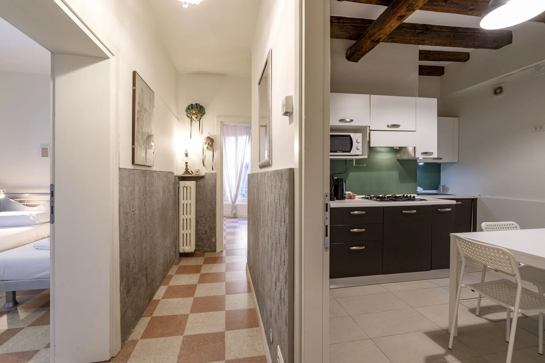 Un pasillo de baldosas da a una cocina compacta con zona de comedor.