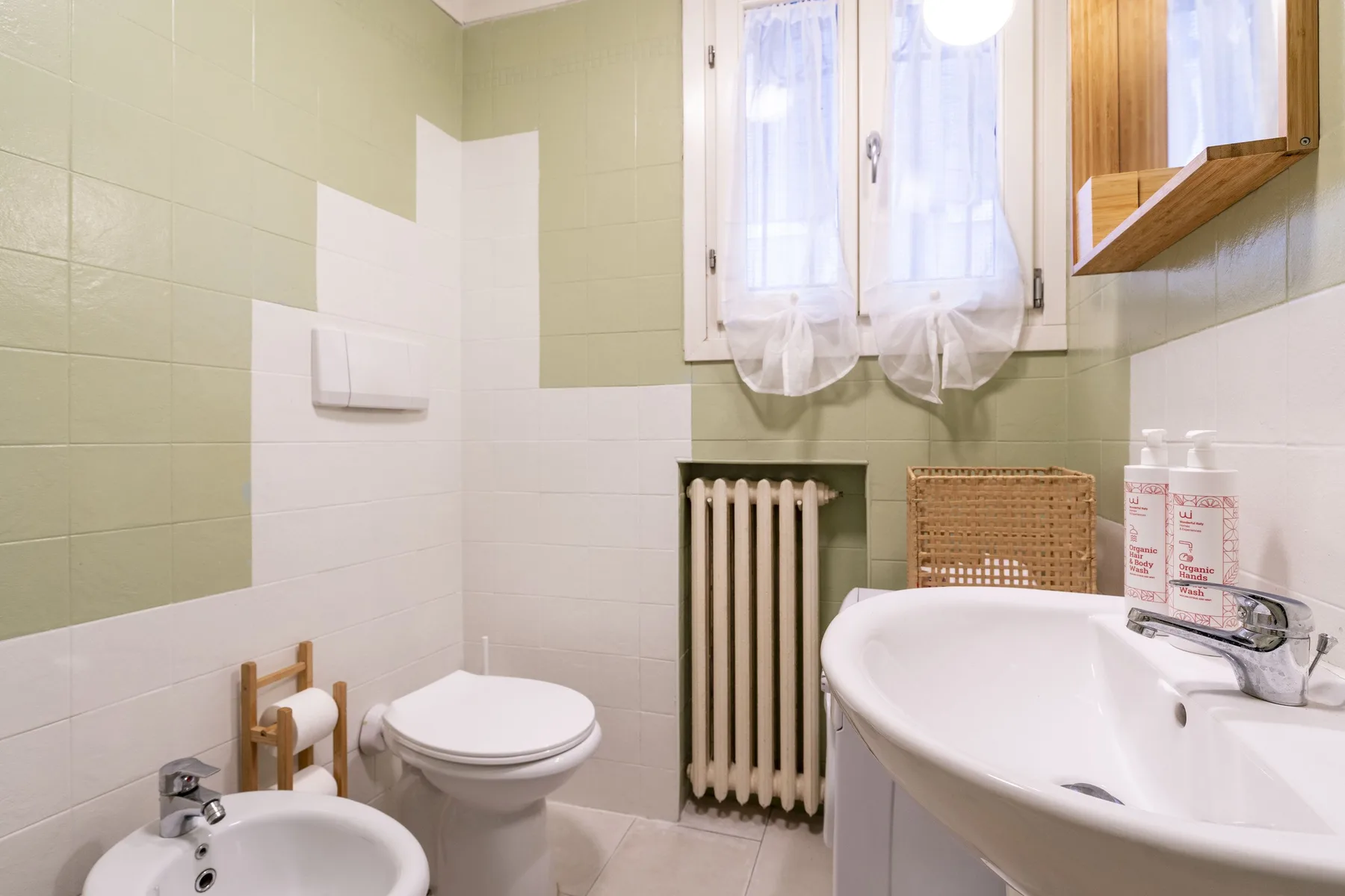 Un baño alicatado con bañera, inodoro y ventana.