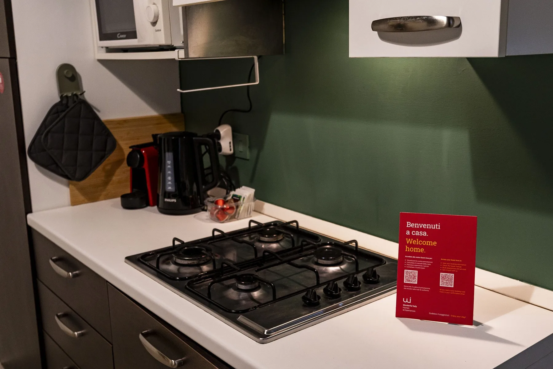 Una encimera de cocina con una placa de gas, pequeños electrodomésticos y una tarjeta roja.